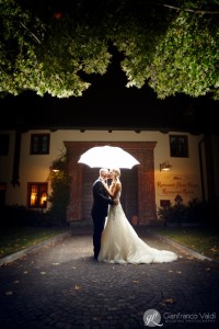 sposi che si baciano sotto l'ombrello